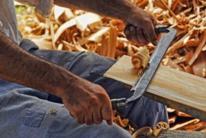 man scraping a wooden bar